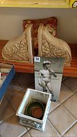 Photo showing the pair of plaster garden wall sconces, the wall hanging of David statue, floral pillow, and plaster garden planter containing a smaller pot inside
