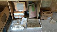 Overall view showing boxes of larger 12x12 ceramic tiles, mosaic tile sheets, and mortar bag stacked against wall.