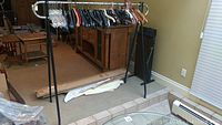 Photo of one metal clothes rack with assortment of clothes hangers on chrome bar and tester's view of Corby trouser press nearby.