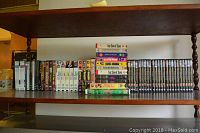 Shelf showing multiple DVDs and VHS tapes including sets of Midsomer Murders, Poldark, Benny Hill, and others