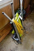 Ryobi portable tile saw folded on its stand with wheels, showing yellow saw body, electric cord, and silver handles.