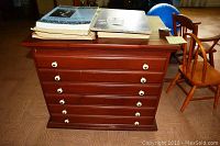 Front view of a six drawer wooden cabinet with white knobs and items on top.