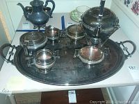 Overview of entire lot on table, includes tray, teapot, kettle stand, sugar bowl, creamer and waste bowls