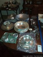 Overview of multiple silver plate items on table including bowls, platters, trays, and napkin rings