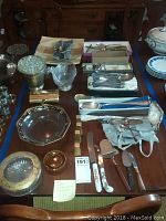 Overview of all items on wooden table including knives, spoons, bowls and covered dish