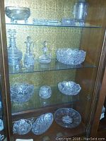Three glass shelves showing top, second and third levels of cut glass pieces