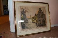 Framed artwork depicting old stone buildings with archways, gold-tone frame visible.