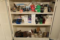 Full cabinet shelf showcasing multiple staplers, tape rolls, clips, and office accessories organized on shelves