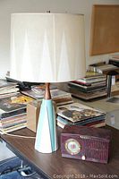 Mid-century modern table lamp and vintage radio shown together on table with vinyl record albums in background
