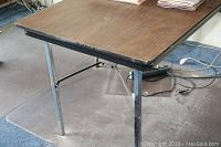 Brown folding table with silver metal legs showing wear and used condition