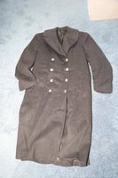 Full view of navy blue trenchcoat laid out flat on light blue carpet showing length and shape.