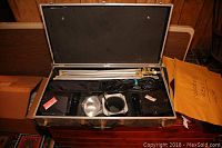 Photo showing the opened carrying case containing folded tripod stands and photo light units with cables and reflectors.