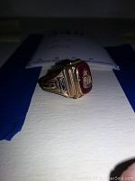 Side profile showing “19” engraving and red enamel bezel with building motif