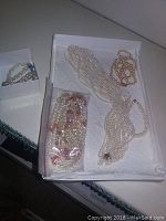 Overview of box containing multiple pearl necklaces, a stretch bracelet and bag of loose beads