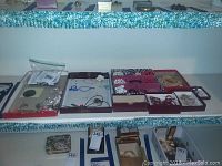 Wide view of trays with assorted costume jewelry including necklaces, brooches, pins, and bracelets arranged on shelves.