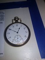 Front view of the Elgin pocket watch showing the white dial with black numerals and subsidiary seconds dial.