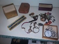 Various watches, stopwatches, watch parts and cases arranged on a white surface.