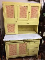 Front view showing overall yellow painted finish, patterned door inserts and white enamel countertop