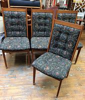 Front view of set of four teak dining chairs with floral upholstered seats and backs.