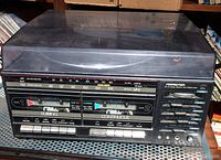Front view of cassette decks and tuner controls on the SoundDesign AM/FM stereo receiver unit, showing dual cassette tape compartments with control buttons and FM/AM frequency dial.