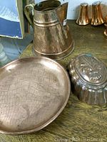 Photo showing the vintage copper pitcher, mold and tray arranged together on a wooden surface with a Campbell's soup can in the background for scale reference