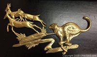 Brass metal wall decor depicting a running cheetah chasing three running antelopes on stylized terrain.