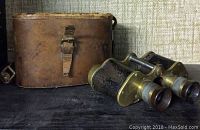 Vintage binoculars with brown leather case, showing front side and general condition.