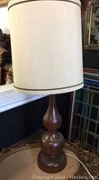 Full view of the wood table lamp with white fabric shade showing height and design.