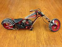 1:10 scale Franklin Mint Harley Davidson metal motorcycle model, red with silver cage design, sitting on wooden surface, viewed from left side