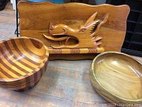 Photo showing carved wooden dragon art piece and two wooden bowls on a table.