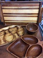 Photo of wood tray, sectional dish, double-section dish with handle and small bowl on a table.