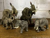 Photo showing the four elephant figurines arranged on a wooden surface with a white wall background.
