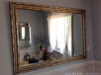 Full view of the composite bamboo look mirror hanging on the wall reflecting window and room