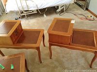 Photo of two matching wooden end tables with leather look inserts and drawers, showing condition including scratches and burn mark.