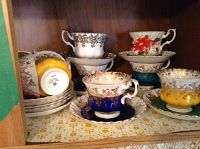 Multiple teacup and saucer sets displayed on wooden shelf