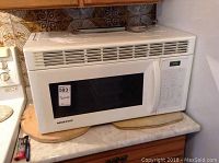 Moffat white microwave oven on kitchen counter, showing full unit including keypad and digital display