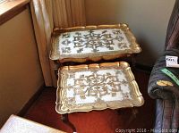 Two Florence Italy nesting tables stacked showing ornate gold and white decorative tops and curved legs.