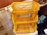 Three-tier yellow plastic storage rack with ventilated basket shelves shown from frontal view.