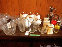 Photo showing seven piece ceramic canister set with copper tops, three large crystal bowls, Dansk glass pitcher, glass and metal coffee carafe, metal and rattan napkin holder, three-piece vintage Made In Japan kitchen set, and small glass bowl.