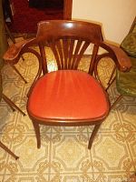 Front view of one chair with reddish vinyl seat with curved wood arms and vertical slats on backrest.