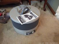 Honeywell Enviracaire HEPA 250 portable air cleaner with power cord and manual on top, sitting on carpeted floor near wood furniture.