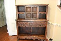 Full front view of vintage wooden hutch showing carved front drawer panel, closed cabinet doors, and open shelving.