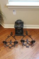 Photo showing the vintage lantern and two matching wrought iron wall sconces placed on a wooden floor against a wall.