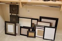 Photo of various picture frames arranged, showing a variety of sizes and wood finishes, with two metal frames at the back.