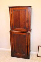 Front view of the tall vintage wooden cabinet showing two paneled doors, top and bottom sections.