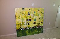 Full view of 48x48 modern abstract oil painting from a distance leaning against beige wall and carpeted floor