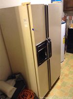 Side view of Kenmore side-by-side refrigerator and freezer showing ice and water dispenser on door, some scratches visible.