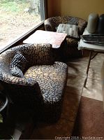 Two swivel chairs with dark gold and black patterned upholstery, accompanied by three throw pillows of varying black and white patterns.