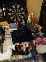 Electronic dart board with various items on table including shower curtains and basket