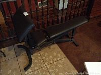 Side view of black adjustable workout bench with padded cushions and metal frame.